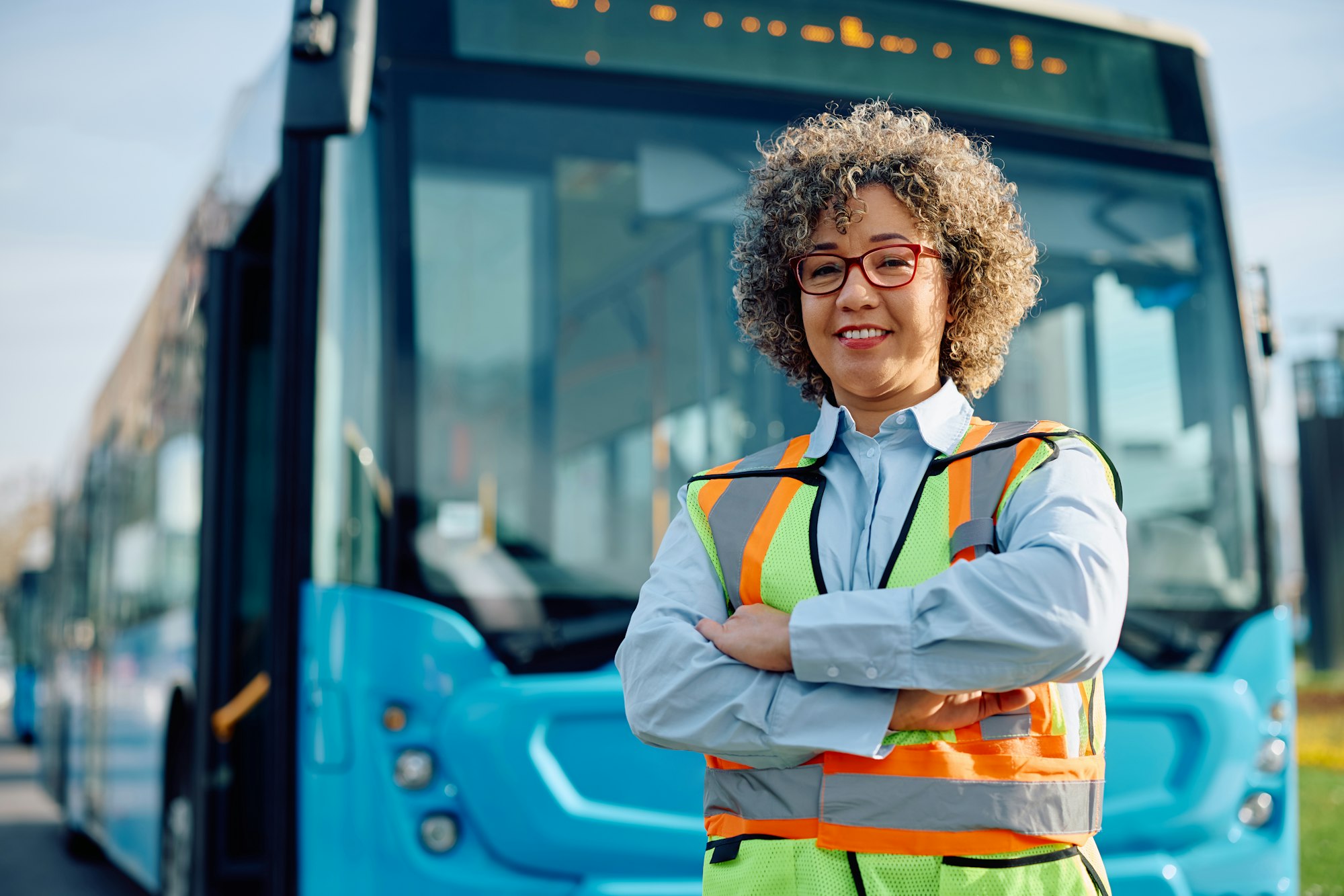 Confident female bus driver at the station looking at camera after complete online cpc courses